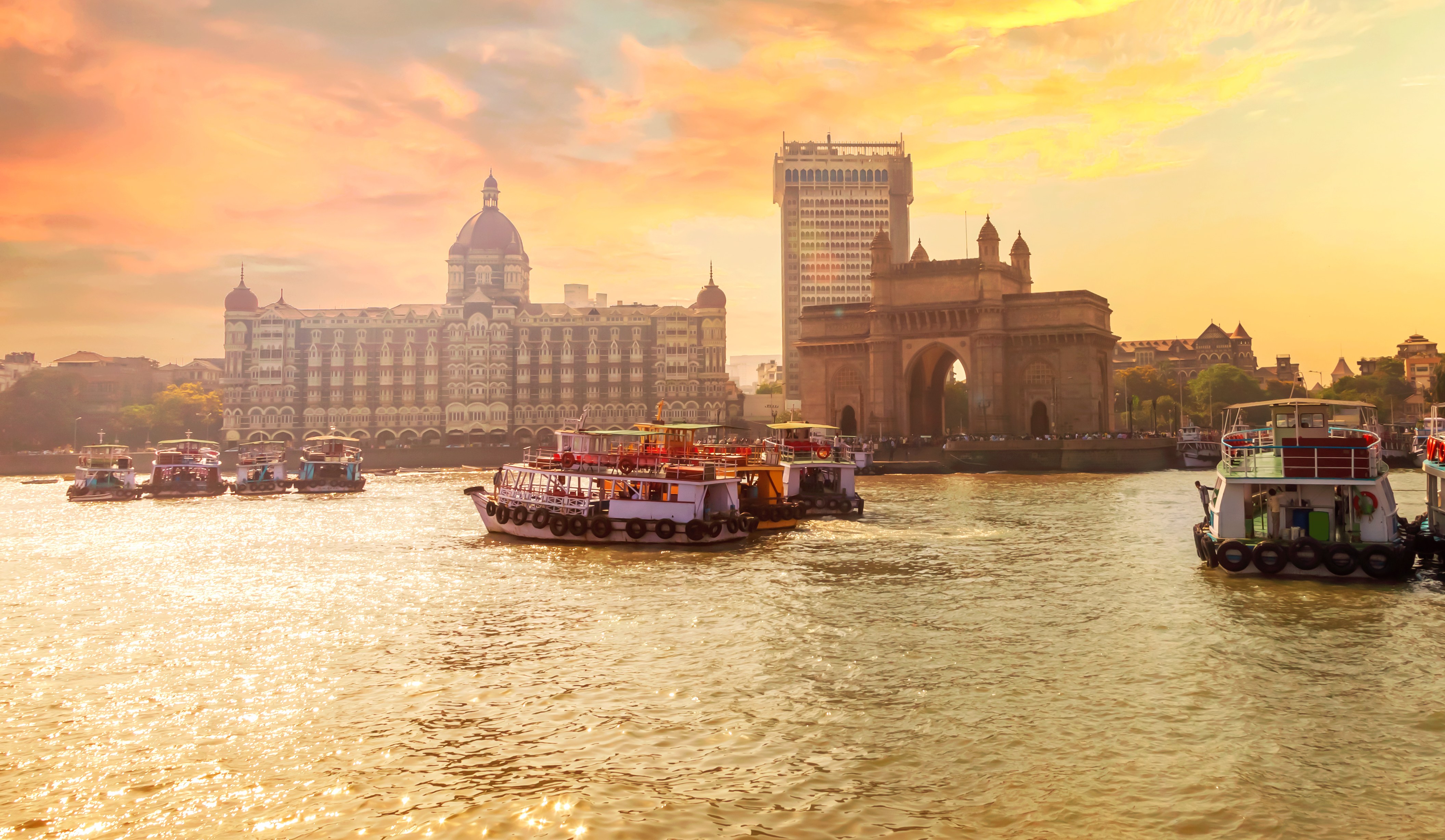 Sunset view of the Gateway of India in Mumbai, with boats in the foreground.
