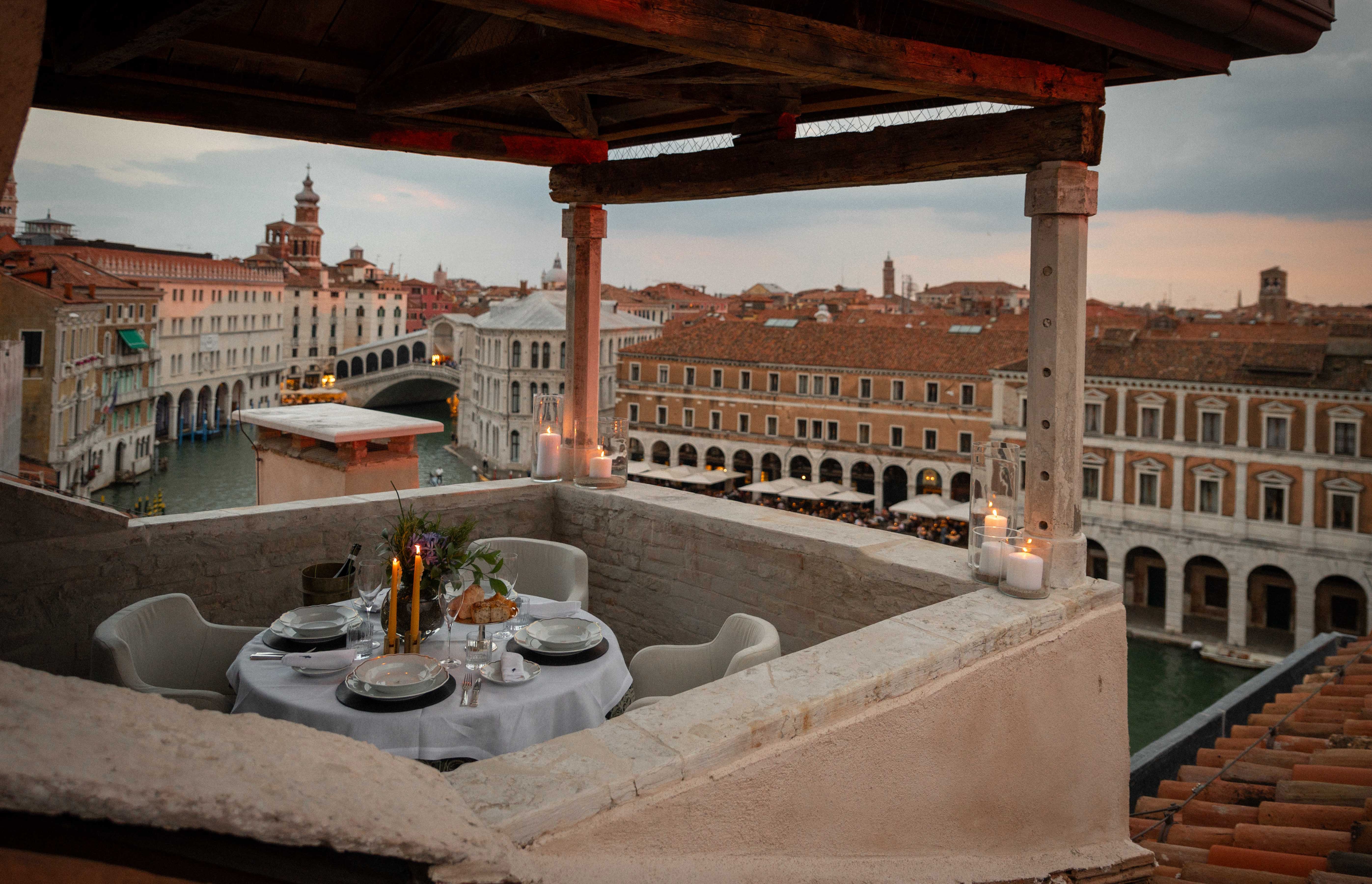 Romantic dinner table on a Venice rooftop terrace overlooking the city.