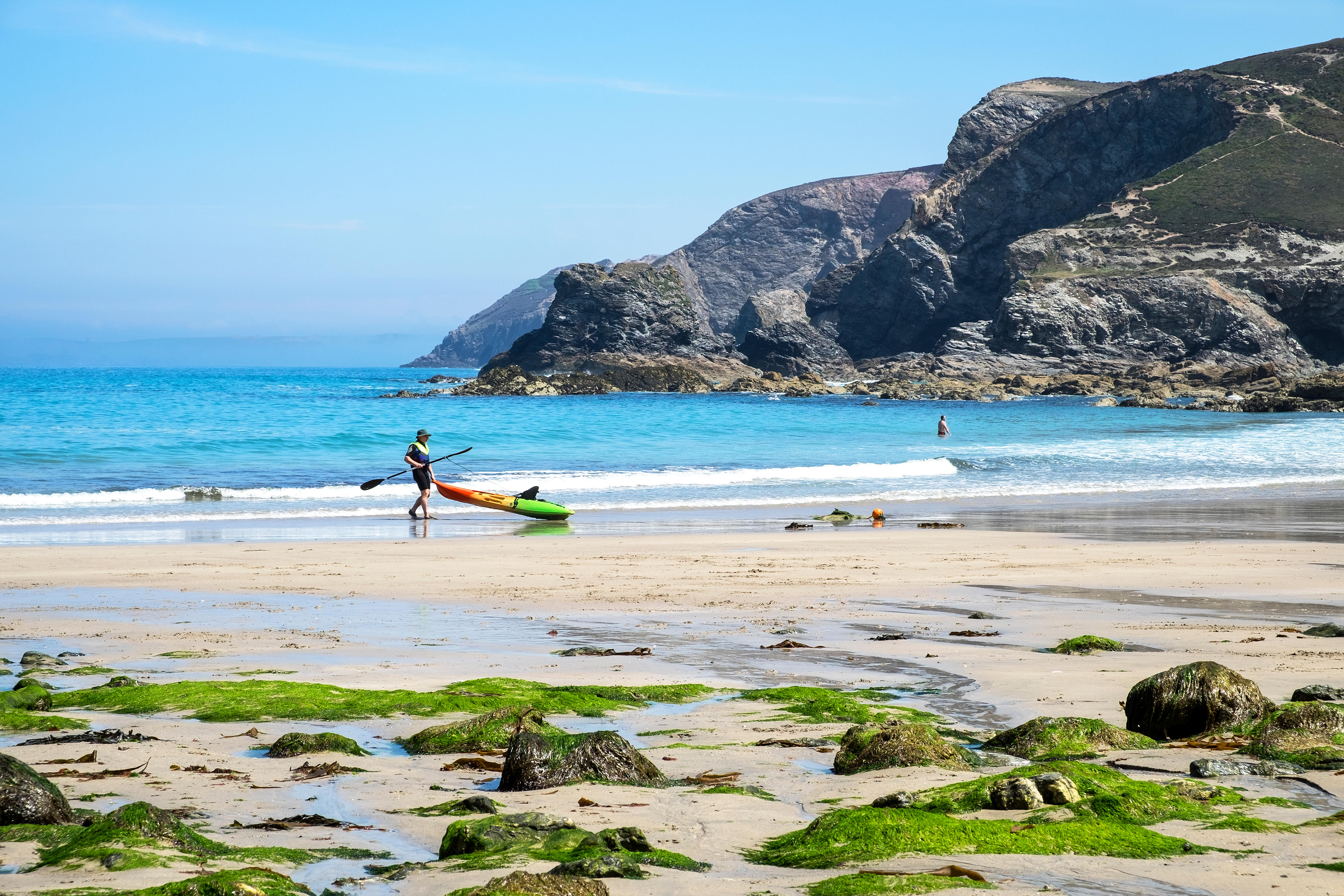 Person carrying kayak on Trevaunance Cove beach in Cornwall.