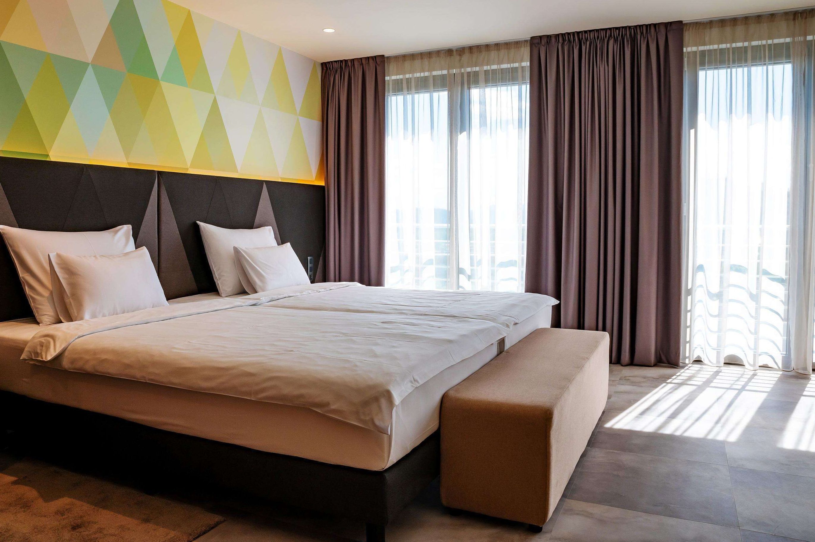 Hotel room with a double bed and geometric patterned wall.