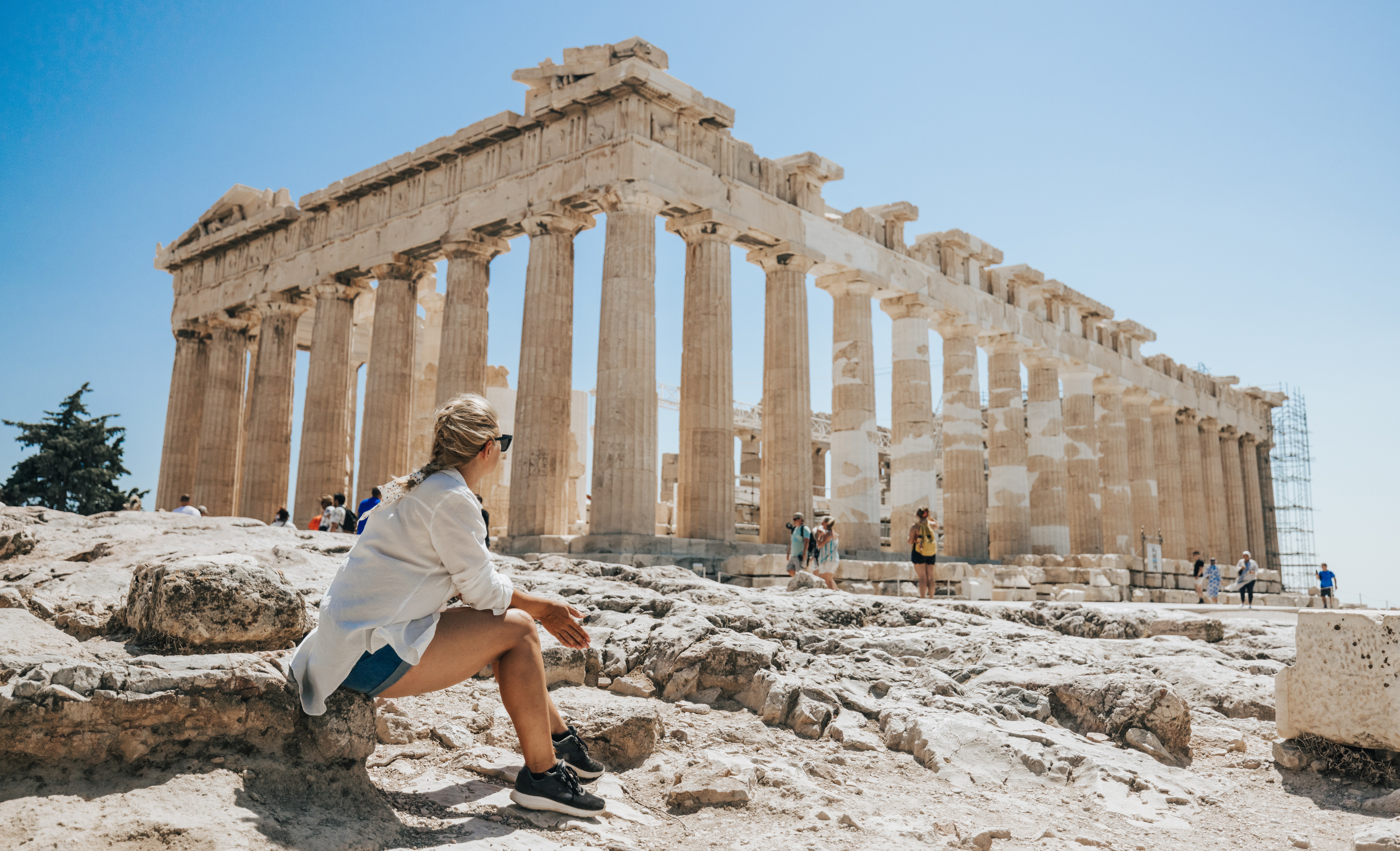 Woman sitting and looking at the Parthenon.