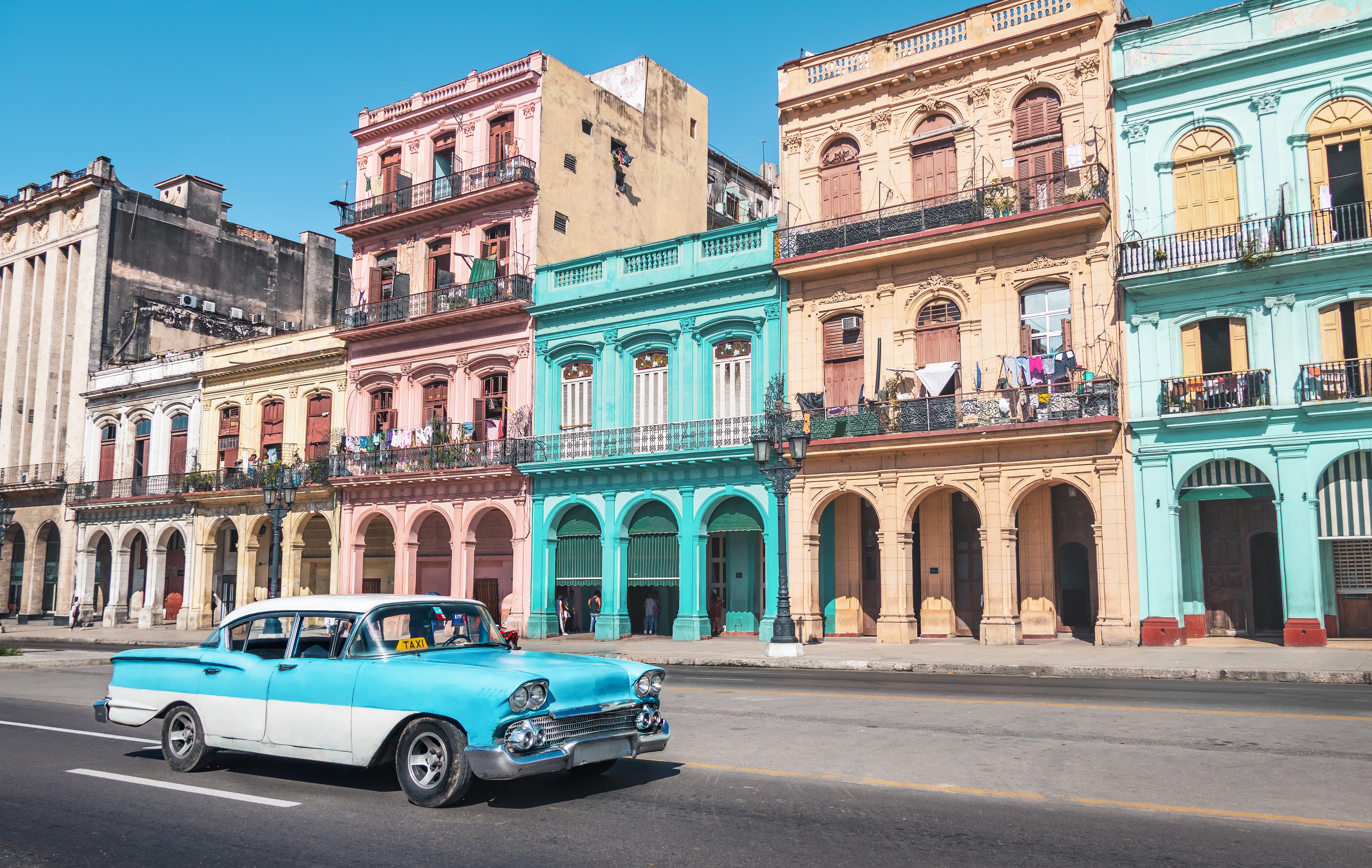 Classic car passing by colorful buildings in Old Havana, Cuba.