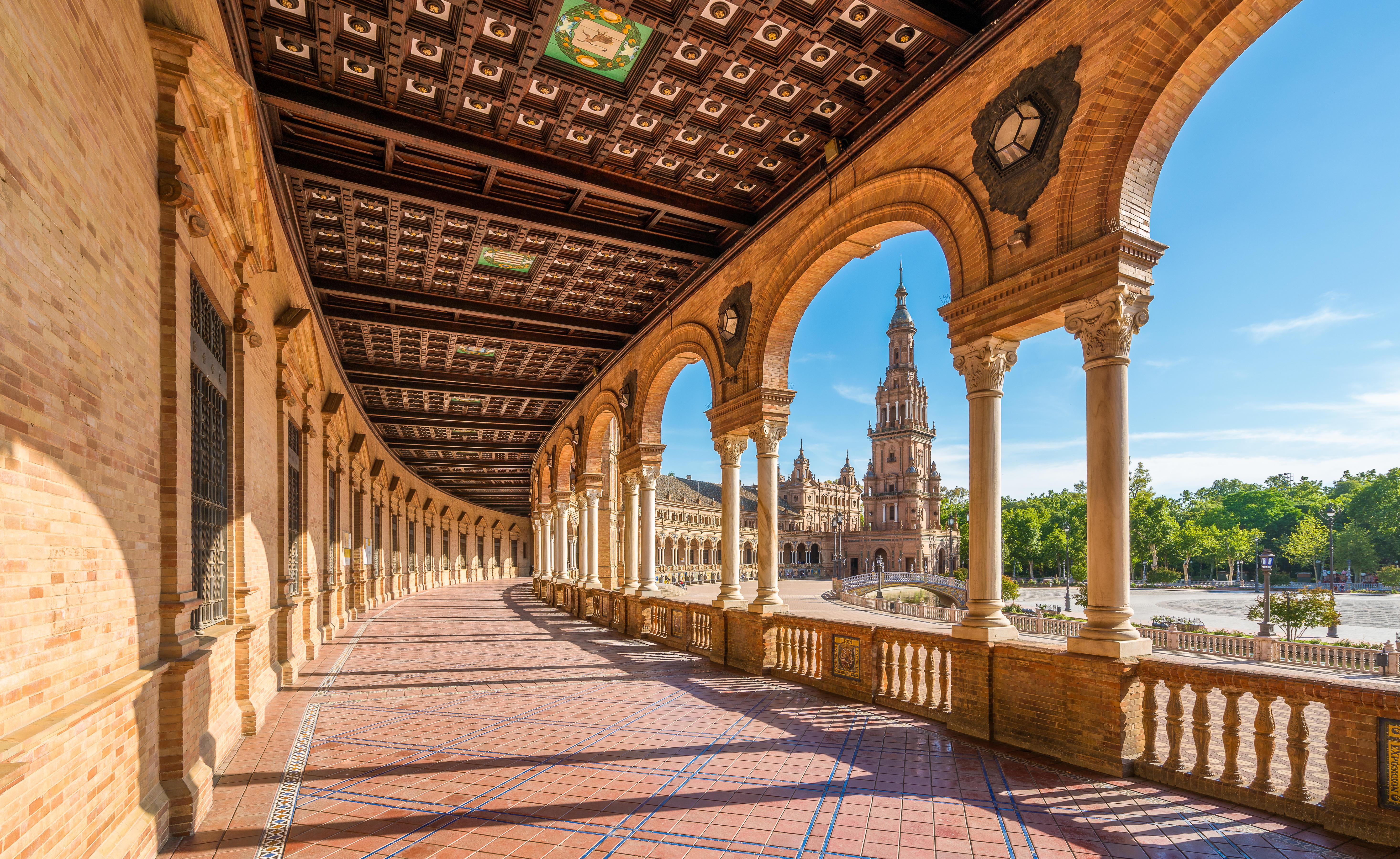 Plaza de España in Seville, Spain, viewed from a colonnaded walkway.